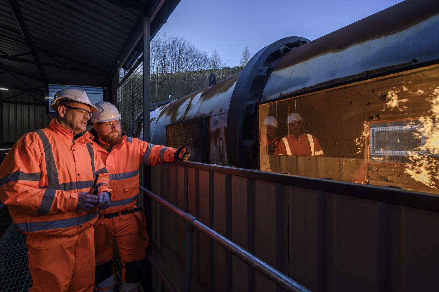 Asphalt Burner Services engineers monitoring the burner flame through an asphalt plant dryer inspection window